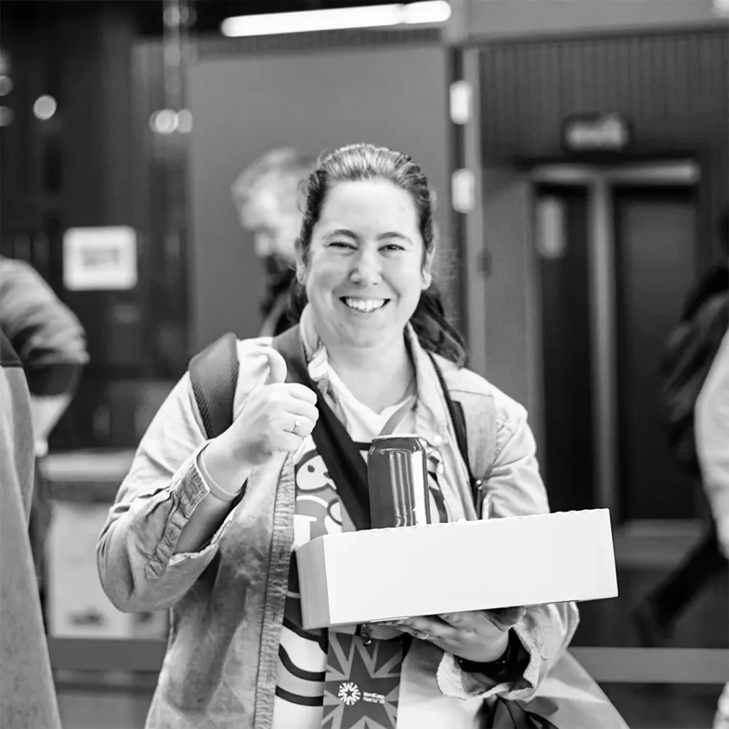 Fotografía de Marta Torre mirando al frente, sonriente y con una caja de comida y una lata de un refresco.